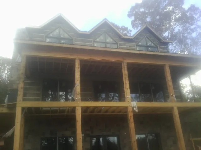 Dormers and porch framing on a large log home under construction — Roof Coating work by our crew in Billings